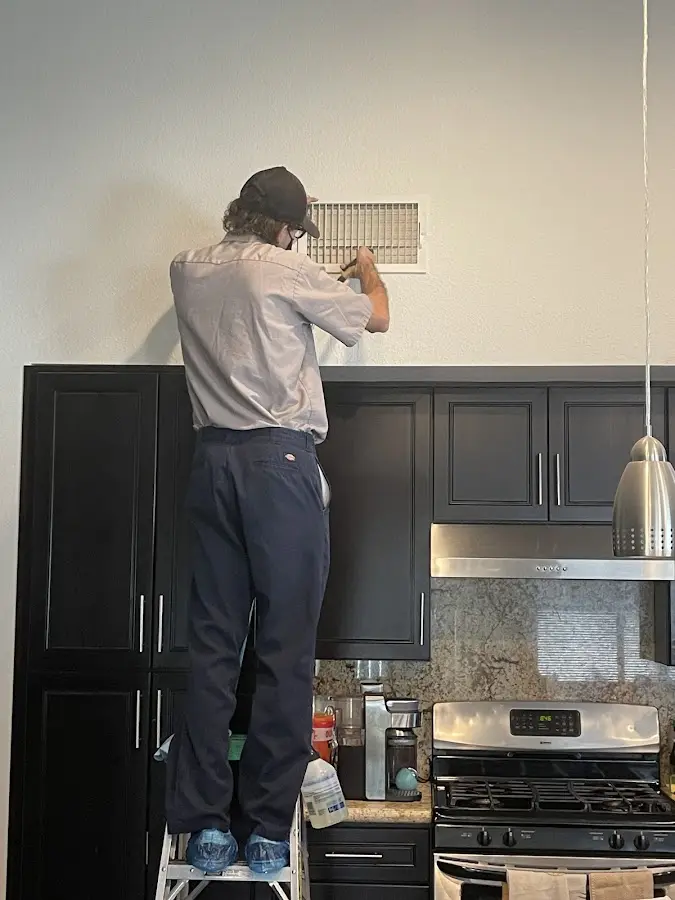 Technician inspecting an air vent during HVAC service in La Riviera